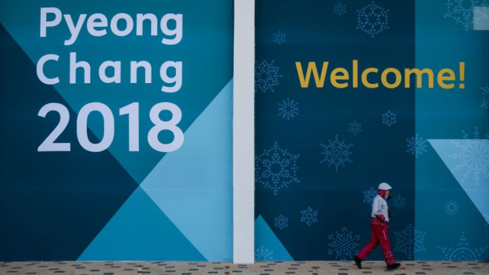 Dobrovoľník kráča okolo obrovského plagátu v olympijskom parku pred zimnými olympijskými hrami 5. februára 2018 v juhokórejskom Kangnunge. 