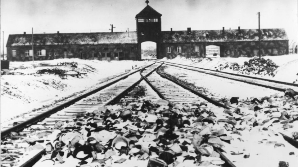 Na snímke z prelomu februára a marca 1945 vidno vstup do koncentračného tábora Osvienčim (Auschwitz-Birkenau) v Poľsku. Železničné koľaje smerujúce do koncentráku sú pokryté snehom.