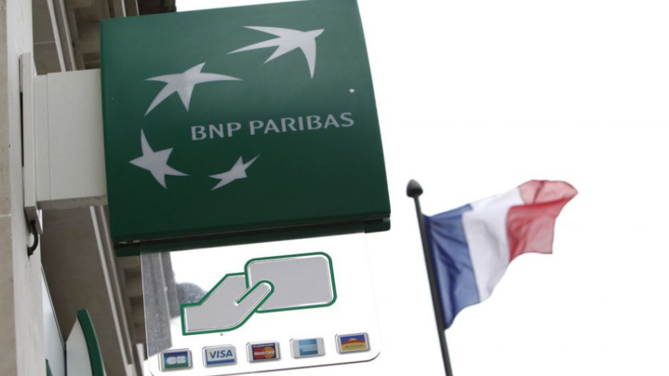Francúzska zástava vedľa logo francúzskej banky BNP Paribas v Paríži.