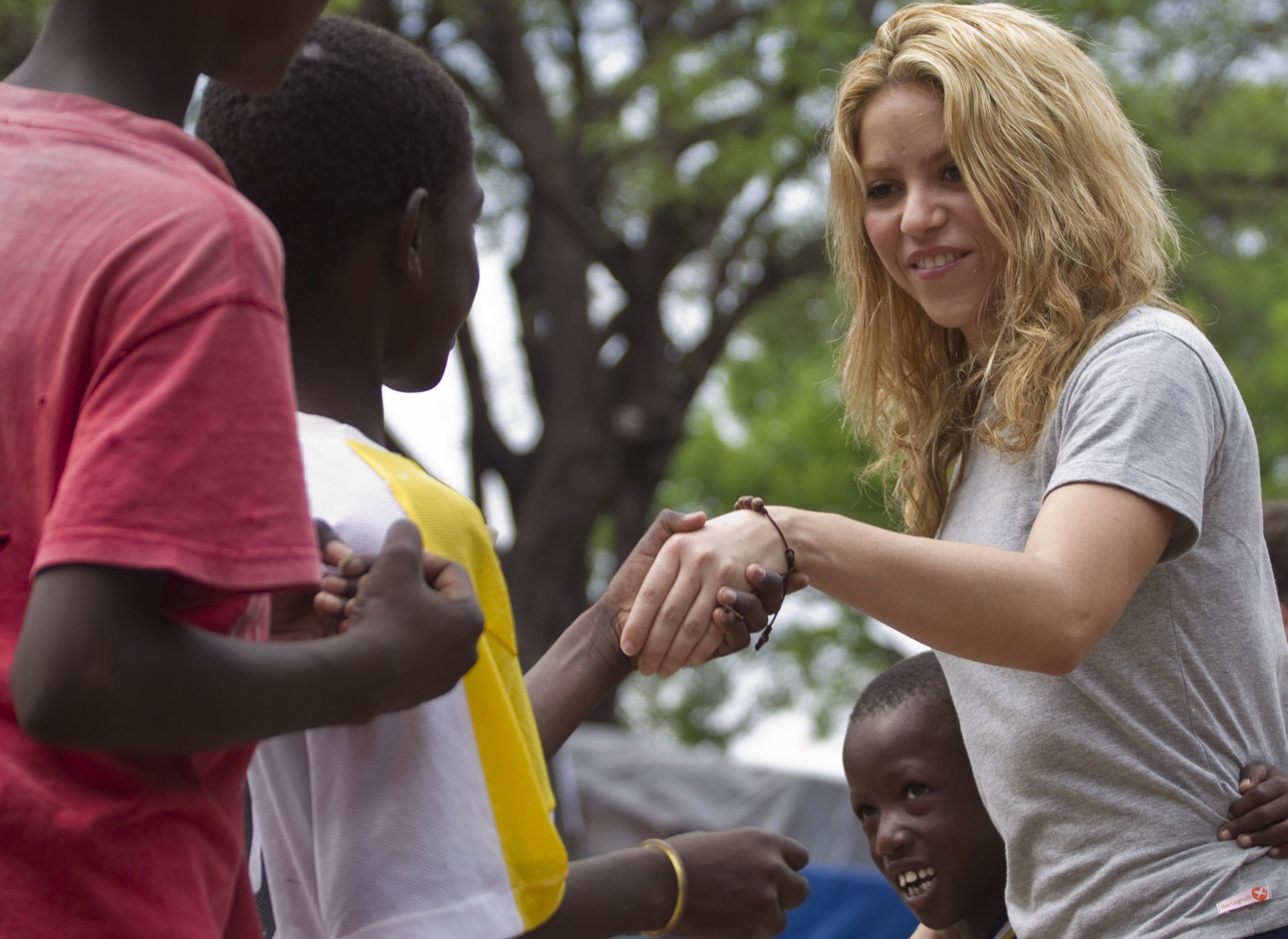 Kolumbijská speváčka Shakira pozdravuje deti počas návštevy provizórneho tábora pre ľudí bez domova v areáli golfového klubu Petionville v Port-au-Prince 11. apríla 2010.