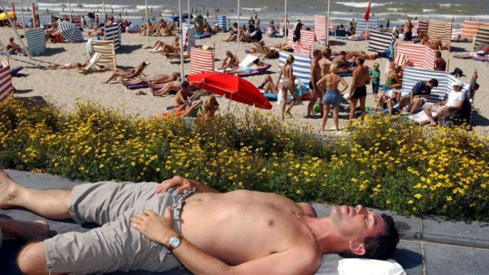 Nemenovaný muž vychutnáva slnečné lúče na pláži v belgickom Ostende. 