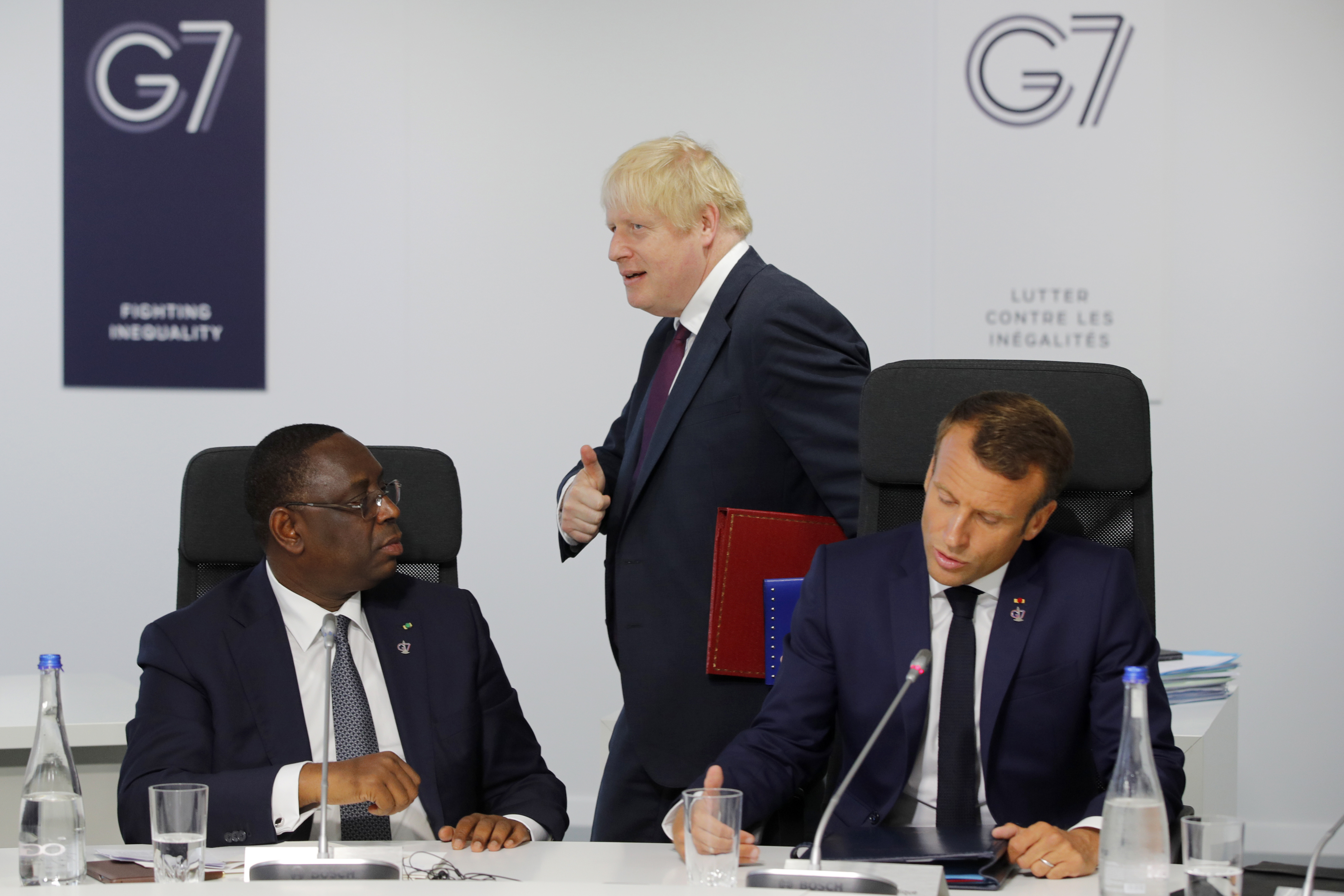 a snímke britský premiér Boris Johnson prechádza okolo francúzskeho prezidenta Emmanuela Macrona (vpravo) a senegalského prezidenta Macky Sallu počas rokovania pracovnej skupiny G7 Partnership with Africa lídrov krajín G7 a predstaviteľov afrických krajín na summite lídrov krajín skupiny G7 v juhofrancúzskom Biarritzi 25. augusta 2019.