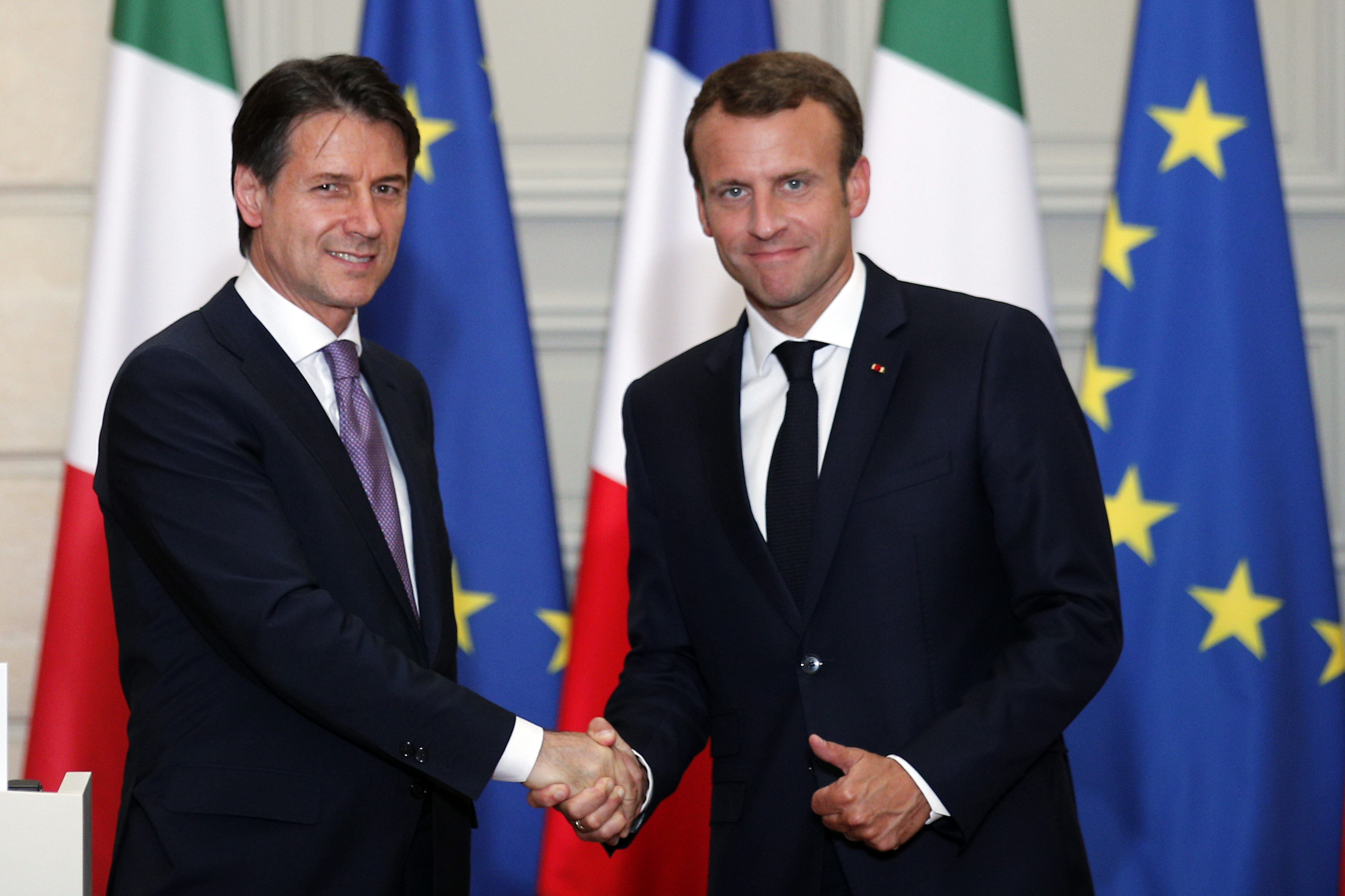 Francúzsky prezident Emmanuel Macron (vpravo) si podáva ruku s talianskym premiérom Giuseppeom Contem