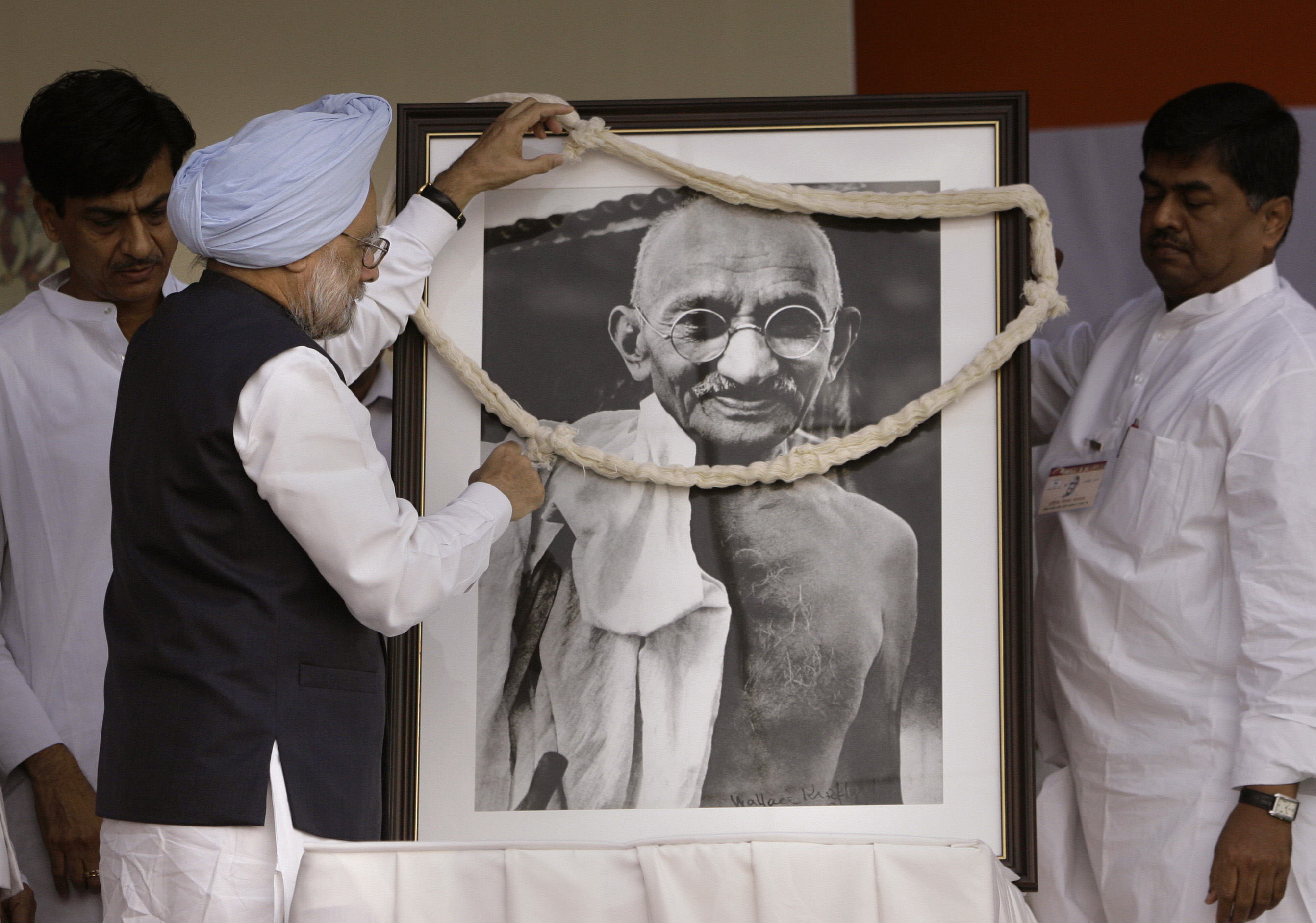 Bývalý indický premiér Manmohan Singh vešia na portrét Mahatmu Gándhího kvetinový veniec, archívna snímka