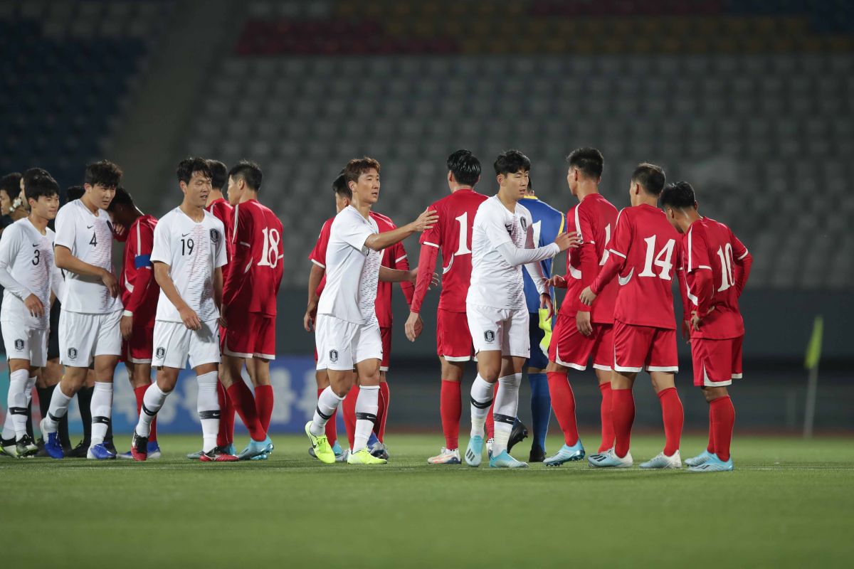 Futbalisti Južnej Kórey (v bielom) a Severnej Kórey (v červenom) si podávajú ruky po remíze