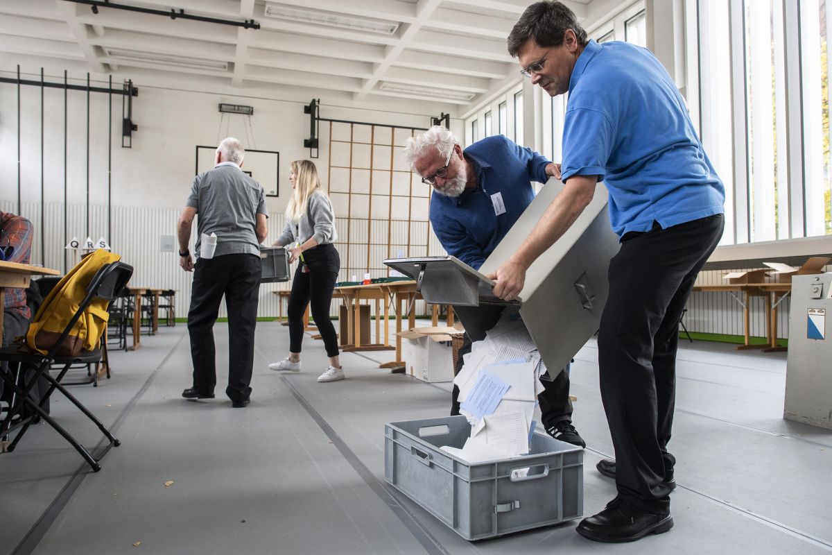 Dobrovoľníci vyprázdňujú box s hlasovacími lístkami počas parlamentných volieb vo volebnej miestnosti v Zürichu 20. októbra 2019