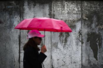 Žena kráča s dáždnikom pred  pozostatkami Berlínskeho múru po oslavách 30. výročia pádu Berlínskeho múru a znovuzjednotení Nemeckej demokratickej republiky (NDR) a Nemeckej spolkovej republiky (NSR) v Berlíne