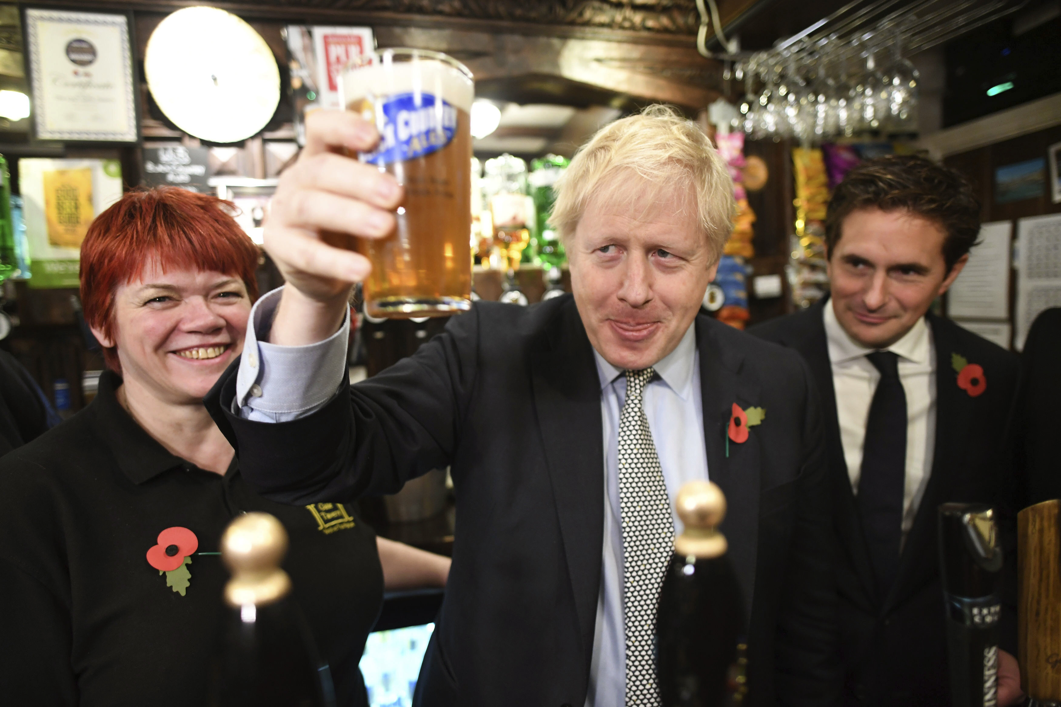 Britský premiér Boris Johnson (uprostred) pózuje s načapovaným pivom vedľa britského ministra obrany Johnnyho Mercera (vpravo) počas jeho stretnutia s vojnovými veteránmi v rámci predvolebnej kampane vládnej Konzervatívnej strany v anglickom meste Wolverhampton 11. novembra 2019. Britský parlament nedávno schválil návrh premiéra Borisa Johnsona, na základe ktorého sa 12. decembra uskutočnia predčasné voľby.