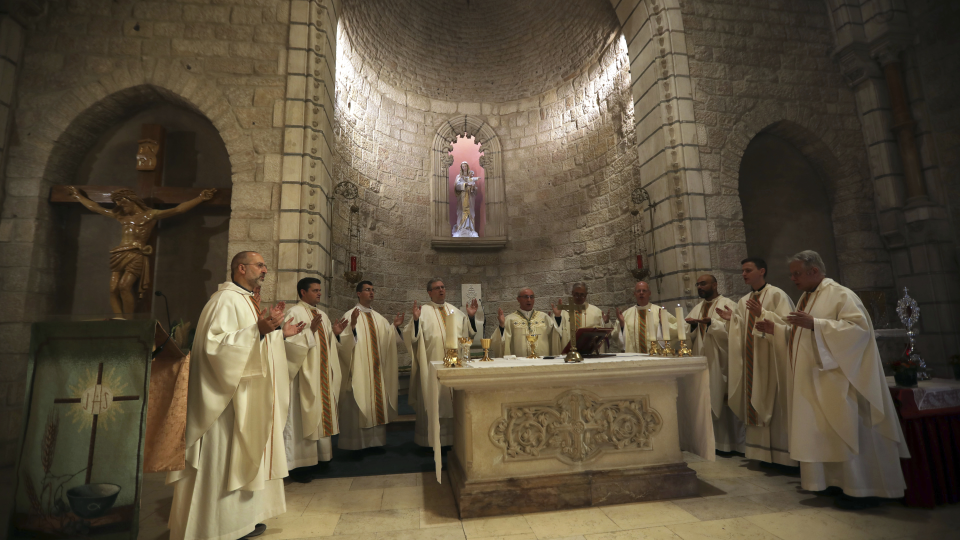 WA 23 Jeruzalem - Kňazi sa modlia vedľa relikvie - časti dreveného fragmentu pochádzajúceho údajne z jasličiek, v ktorých bol po narodení uložený Ježiš v kostole Notre Dame v Jeruzaleme 29. novembra 2019. Celá relikvia sa nachádza v Bazilike Panny Márie Väčšej (Santa Maria Maggiore) v Ríme. Podľa tradície má relikvia viac ako 2000 rokov a pochádza údajne z jasličiek, v ktorých bol po narodení uložený Ježiš. Do Vatikánu sa relikvia dostala v 7. storočí.Mesto Betlehem, ležiace na západnom brehu Jordánu, pred Vianocami vždy čelí náporu kresťanských pútnikov prichádzajúcich z celého sveta. Ku kresťanstvu sa hlási asi jedno percento obyvateľov Západného brehu, pásma Gazy a východného Jeruzalema.
