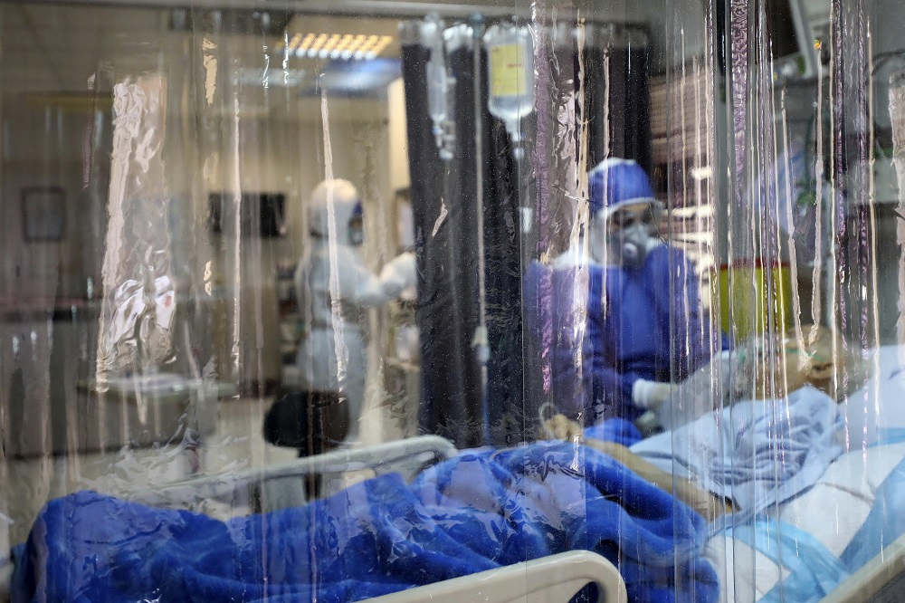 Na snímke je lekár v ochrannom obleku, ktorý lieči pacienta infikovaného koronavírusom v nemocnici v iránskom Teheráne 1. marca 2020.