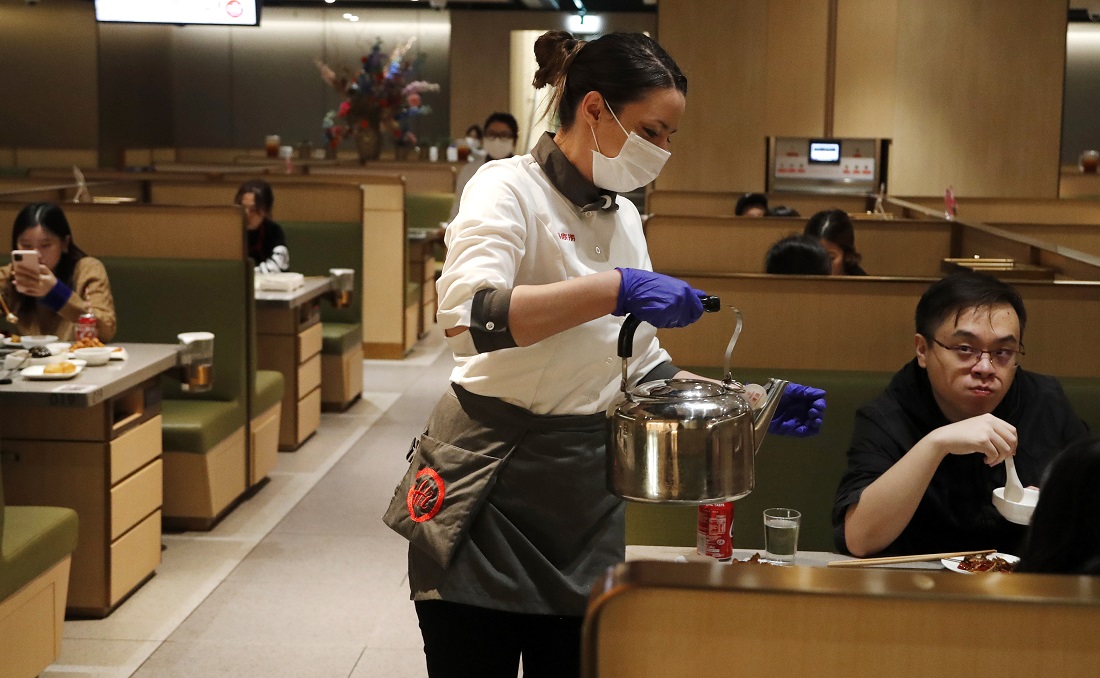 Časníčka s ochranným rúškom na tvári obsluhuje zákazníka v čínskej reštaurácii v Londýne