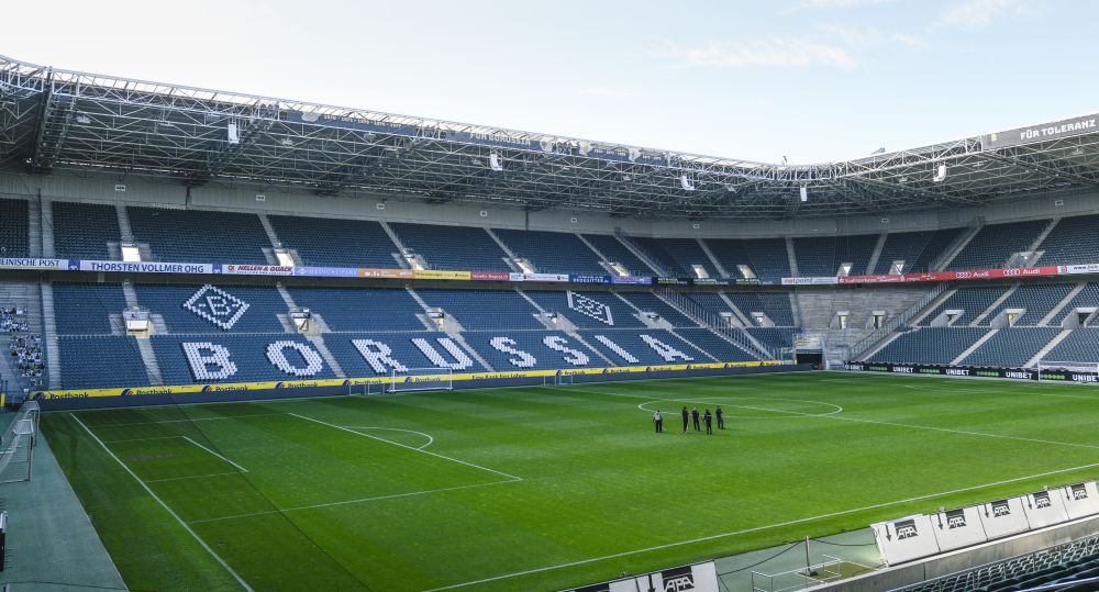 Na snímke zopár zamestnancov klubu stojí na trávniku prázdneho futbalového štadióna bundesligového futbalového klubu Borussia Mönchengladbach.