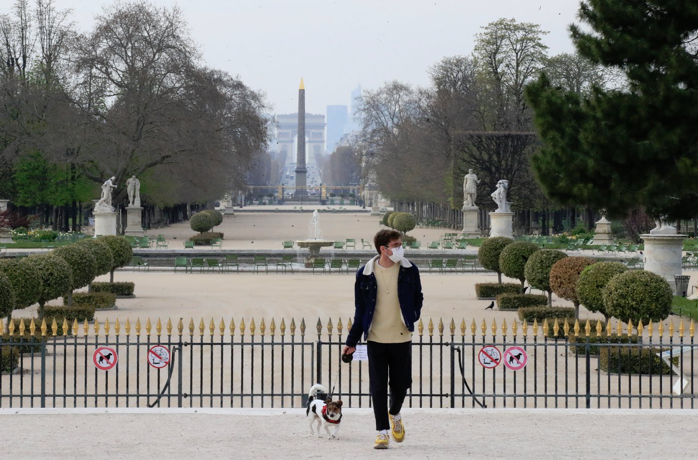 Muž s ochranným rúškom sa prechádza so svojím psom popri Tuilerijských záhradách v Paríži, archívna snímka.