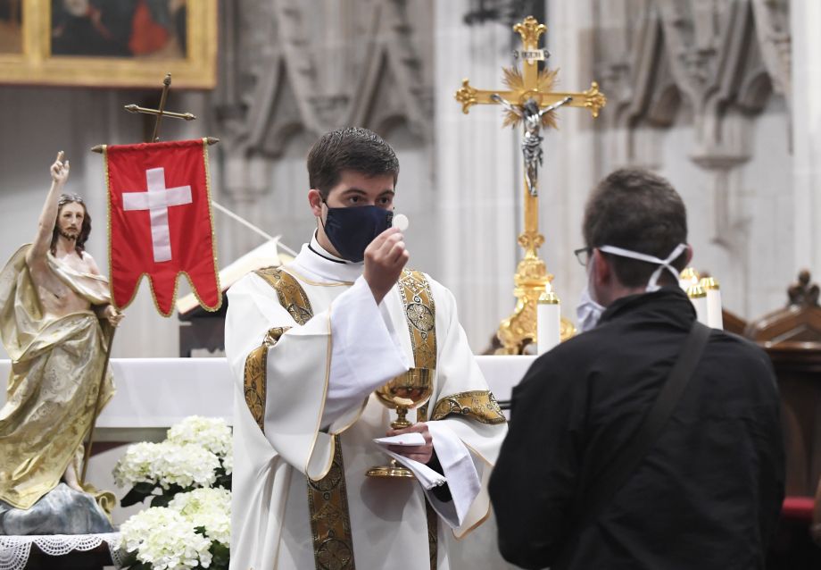Na snímke veriaci prijíma hostiu od kňaza s ochranným rúškom počas verejnej bohoslužby v Dóme sv. Alžbety.