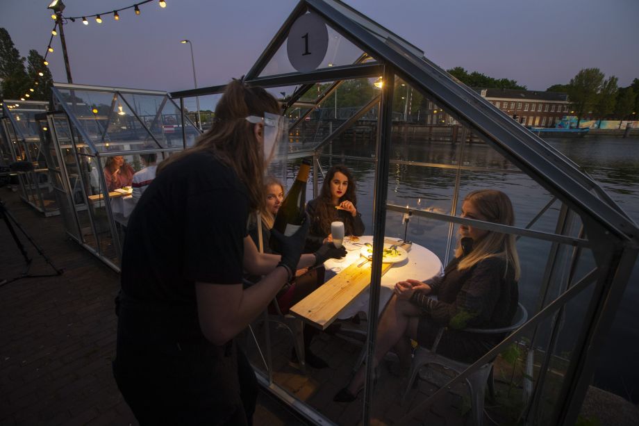 Dobrovoľníci sedia v reštaurácii Mediamatic v izolovaných malých skleníkoch, aby sa obmedzilo šíreniu nákazy nového koronavírusu 5. mája 2020 v Amsterdame.