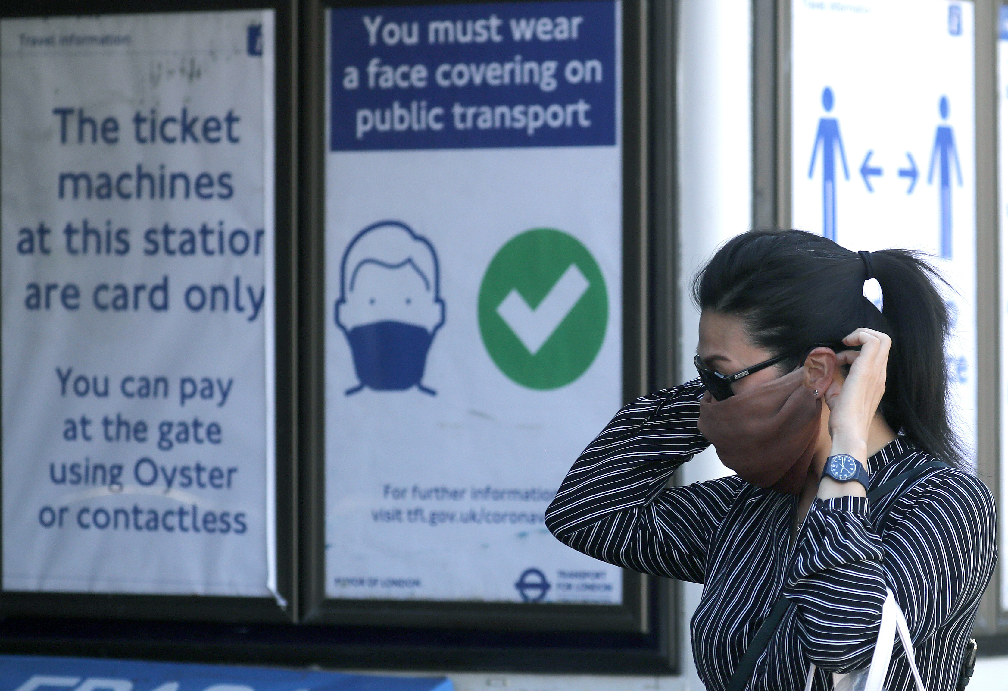 Cestujúca si dáva na tvár rúško pred vstupom na zastávku metra v Londýne v pondelok 15. júna 2020.
