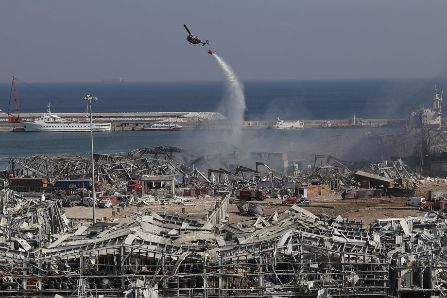 Vojenský vrtuľník vylieva vodu z vaku na budovy po masívnych výbuchoch v prístave v libanonskom hlavnom meste Bejrút