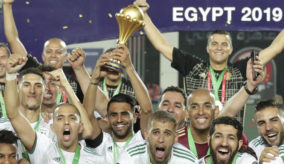 Uprostred kapitán alžírskej futbalovej reprezentácie Riyad Mahrez drží nad hlavou pohárovú trofej víťaza Afrického pohára národov po víťazstve vo finále nad Senegalom 1:0 v egyptskej Káhire 19. júla 2019.